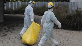 Petugas kesehatan membawa limbah medis di sela melakukan tes usap (swab test) PCR di Jakarta, Jumat (29/10/2021). [Suara.com/Angga Budhiyanto]