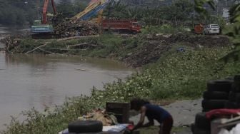 Petugas dari Suku Dinas Sumber Daya Air Jakarta Pusat mengoperasikan alat berat untuk mengangkut sampah di sepanjang aliran Kanal Banjir Barat di kawasan Tanah Abang, Jakarta, Jumat (29/10/2021). [Suara.com/Angga Budhiyanto]