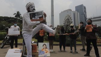 Relawan melakukan aksi teatrikal di kawasan Patung Kuda Arjuna Wiwaha, Jakarta, Senin (1/11/2021). [Suara.com/Angga Budhiyanto]