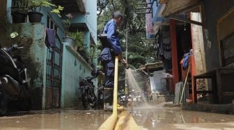 Petugas Penanggulangan Kebakaran dan Penyelamatan (Gulkarmat) membersihkan lumpur sisa banjir di Kelurahan Cipinang Melayu, Jakarta, Selasa (2/11/2021). [Suara.com/Angga Budhiyanto]