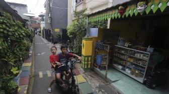 Dua anak bermain di dekat ornamen gigi balang yang menghiasi salah satu rumah di kawasan Kampung Sentra Kreatif, RW 006 Kota Bambu Selatan, Palmerah, Jakarta, Rabu (3/11/2021). [Suara.com/Angga Budhiyanto]