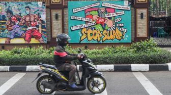 Kendaraan melintas di depan mural yang berisi kritik terhadap Polri di Jalan Trunojoyo, Jakarta Selatan, Sabtu (6/11/2021). [Suara.com/Alfian Winanto]