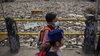 Warga berjalan di samping sampah yang menumpuk di Kali Dadap yang dipenuhi sampah di Kosambi, Kabupaten Tangerang, Banten, Jumat (12/11/2021). ANTARA FOTO/Fauzan