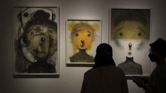 Pengunjung melihat karya seni yang ditampilkan dalam pameran seni bertajuk Daydreaming Face di RUCI Art Space, Kebayoran Baru, Jakarta, Sabtu (13/11/2021). [Suara.com/Angga Budhiyanto]