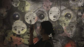 Pengunjung memotret karya seni yang ditampilkan dalam pameran seni bertajuk Daydreaming Face di RUCI Art Space, Kebayoran Baru, Jakarta, Sabtu (13/11/2021). [Suara.com/Angga Budhiyanto]