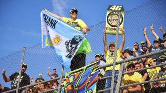 Fans pebalap Italia Valentino Rossi bersorak dari tribun selama balapan MotoGP Grand Prix Valencia di arena pacuan kuda Ricardo Tormo di Cheste, pada 14 November 2021. 
JOSE JORDAN / AFP