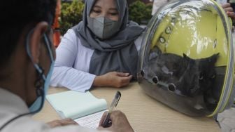 Warga membawa kucing peliharaan usai divaksinasi rabies gratis di halaman Kantor Kelurahan Kebon Baru, Tebet, Jakarta, Selasa (16/11/2021). [Suara.com/Angga Budhiyanto]