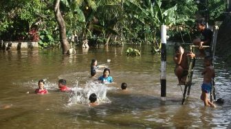 Sejumlah anak berenang di lapangan volley yang terendam banjir di Desa Semuntai, Kabupaten Sanggau, Kalimantan Barat, Senin (15/11/2021).  ANTARA FOTO/Jessica Helena Wuysang