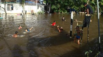 Sejumlah anak berenang di lapangan volley yang terendam banjir di Desa Semuntai, Kabupaten Sanggau, Kalimantan Barat, Senin (15/11/2021).  ANTARA FOTO/Jessica Helena Wuysang