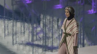 Model memperagakan busana muslim pada gelaran Jakarta Muslim Fashion Week (JMFW) di Stadion Aquatic, Gelora Bung Karno, Jakarta, Kamis (18/11/2021). [Suara.com/Angga Budhiyanto]