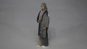 Model memperagakan busana muslim pada gelaran Jakarta Muslim Fashion Week (JMFW) di Stadion Aquatic, Gelora Bung Karno, Jakarta, Kamis (18/11/2021). [Suara.com/Angga Budhiyanto]