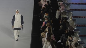 Model memperagakan busana muslim pada gelaran Jakarta Muslim Fashion Week (JMFW) di Stadion Aquatic, Gelora Bung Karno, Jakarta, Kamis (18/11/2021). [Suara.com/Angga Budhiyanto]