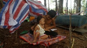 Dua anak bermain di tempat pengungsian di dalam hutan Desa Sungai Rambai, Kelurahan Mekar Jaya, Kabupaten Sintang, Kalimantan Barat, Rabu (17/11/2021). ANTARA FOTO/Jessica Helena Wuysang