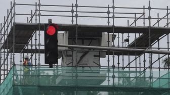 Sejumah kendaraan melintas di samping tugu jam yang dipasang perancah di Jalan MH. Thamrin, Jakarta, Jumat (19/11/2021). [Suara.com/Angga Budhiyanto]