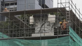 Pekerja memasang perancah saat akan melakukan pengerjaan relokasi tugu jam di Jalan MH. Thamrin, Jakarta, Jumat (19/11/2021). [Suara.com/Angga Budhiyanto]