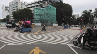 Sejumah kendaraan melintas di samping tugu jam yang dipasang perancah di Jalan MH. Thamrin, Jakarta, Jumat (19/11/2021). [Suara.com/Angga Budhiyanto]