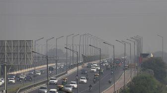 Komuter berjalan di sepanjang jalan di tengah kabut asap tebal di New Delhi, India, pada (16/11/2021). [MONEY SHARMA / AFP]