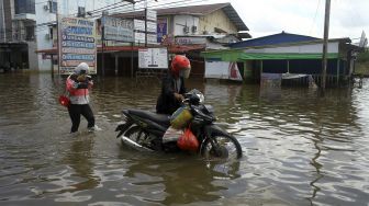 Dua warga melintasi banjir di kawasan Lintas Melawi yang dilanda banjir di Kota Sintang, Kalimantan Barat, Kamis (18/11/2021). [ANTARA FOTO/Jessica Helena Wuysang]