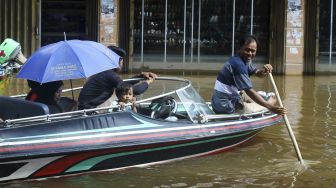 Seorang pria mendayung kapal saat hendak keluar dari kawasan Pasar Sungai Durian yang dilanda banjir di Sintang, Kalimantan Barat, Kamis (18/11/2021). [ANTARA FOTO/Jessica Helena Wuysang]