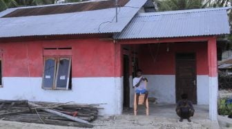 Dua orang remaja bersantai di depan rumahnya yang sudah dicat berwarna merah di Kampung Merah Putih di Desa Oeseli, Kabupaten Rote Ndao, NTT, Jumat (19/11/2021). [ANTARA FOTO/Kornelis Kaha]