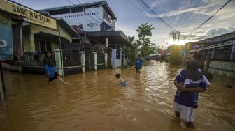 Warga berjalan melintasi banjir yang kembali merendam permukiman di Kecamatan Barabai, Kabupaten Hulu Sungai Tengah, Kalimantan Selatan, Jumat (19/11/2021). [ANTARA FOTO/Bayu Pratama S]