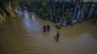 Warga berjalan melintasi banjir yang kembali merendam permukiman di Kecamatan Barabai, Kabupaten Hulu Sungai Tengah, Kalimantan Selatan, Jumat (19/11/2021). [ANTARA FOTO/Bayu Pratama S]