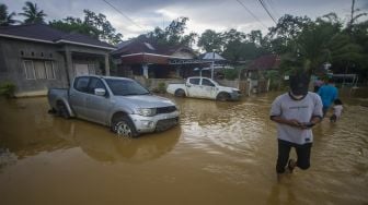 Warga berjalan melintasi banjir yang kembali merendam permukiman di Kecamatan Barabai, Kabupaten Hulu Sungai Tengah, Kalimantan Selatan, Jumat (19/11/2021). [ANTARA FOTO/Bayu Pratama S]