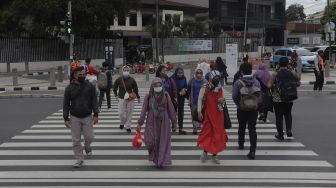 Pekerja menyeberang di 'pelican cross' Tosari saat jam pulang kerja di Jakarta, Selasa (23/11/2021). [Suara.com/Angga Budhiyanto]