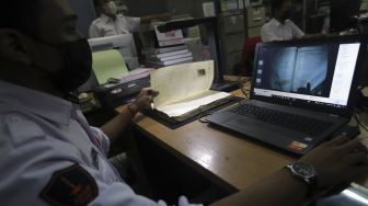 Petugas Dinas Perpustakaan dan Kearsipan (Dispusip) Provinsi DKI Jakarta mendigitalisasikan arsip sekolah di SMAN 77, Cempaka Putih, Jakarta, Rabu (24/11/2021). [Suara.com/Angga Budhiyanto]