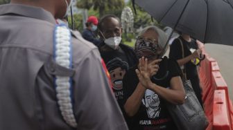 Ibunda korban tragedi semanggi I BR Norma Irmawan, Maria Katarina Sumarsih berdiskusi dengan polisi saat mengikuti aksi Kamisan di depan Istana Merdeka, Jakarta, Kamis (25/11/2021). [Suara.com/Angga Budhiyanto]