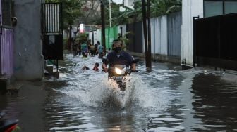 Warga melintasi banjir dengan sepeda motor di Jalan Wijaya Timur, Petogogan, Jakarta Selatan, Jumat (26/11/2021). [Suara.com/Alfian Winanto]