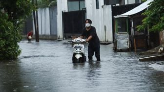 Warga mendorong kendaraannya melewati banjir di Jalan Wijaya Timur, Petogogan, Jakarta Selatan, Jumat (26/11/2021). [Suara.com/Alfian Winanto]