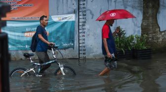 Warga melintasi banjir di Jalan Wijaya Timur, Petogogan, Jakarta Selatan, Jumat (26/11/2021). [Suara.com/Alfian Winanto]