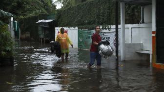 Warga melintasi banjir di Jalan Wijaya Timur, Petogogan, Jakarta Selatan, Jumat (26/11/2021). [Suara.com/Alfian Winanto]