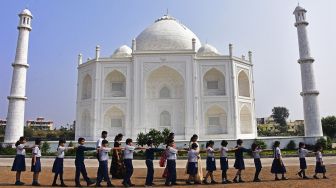 Anak-anak sekolah berjalan melewati replika Taj Mahal selama kunjungan mereka di Burhanpur, negara bagian Madhya Pradesh, India, pada (25/11/2021). [UMA SHANKAR MISHRA / AFP]