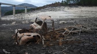 Puing-puing truk terlihat di sebelah reruntuhan bekas desa Aceredo yang biasanya terendam, muncul dari pembangkit listrik tenaga air Waduk Lindoso, Lobios, Provinsi Ourense, Spanyol, pada (22/11/2021). [MIGUEL RIOPA / AFP]