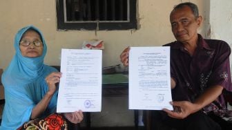 Seorang ibu, Sri Surantini (kiri) didampingi anak pertamanya Gunawan Joko (kanan) menunjukan surat panggilan pengadilan selaku tergugat di Guwokajen, Sawit, Boyolali, Jawa Tengah, Minggu (28/11/2021).  ANTARA FOTO/Aloysius Jarot Nugroho