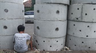 Warga beraktivitas di dekat buis beton drainase vertikal di kawasan Manggarai, Jakarta Selatan, Selasa (30/11/2021). [Suara.com/Alfian Winanto]