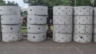 Warga beraktivitas di dekat buis beton drainase vertikal di kawasan Manggarai, Jakarta Selatan, Selasa (30/11/2021). [Suara.com/Alfian Winanto]