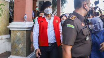 Musisi I Gede Ari Astina atau Jerinx SID berjalan keluar mengenakan rompi tahanan berwarna merah usai menjalani pemeriksaan di Kejaksaan Negeri Jakarta Pusat, Rabu (1/12/2021). [Suara.com/Alfian Winanto]