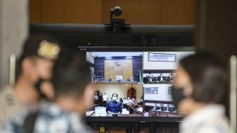 Layar televisi menampilkan jalannya sidang perdana kasus dugaan terorisme dengan terdakwa Munarman yang berjalan secara daring di Pengadilan Negeri Jakarta Timur, Rabu (1/12/2021).  ANTARA FOTO/M Risyal Hidayat