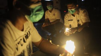 Relawan menyalakan lampu dalam malam renungan Hari AIDS Sedunia di Tanah Abang, Jakarta, Rabu (1/12/2021). [Suara.com/Angga Budhiyanto]