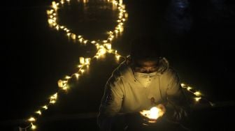 Relawan menyalakan lampu dalam malam renungan Hari AIDS Sedunia di Tanah Abang, Jakarta, Rabu (1/12/2021). [Suara.com/Angga Budhiyanto]