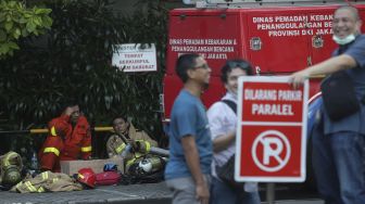 Petugas pemadam kebakara beristirahat usai memadamkan kebakaran yang terjadi di Gedung Cyber 1, Jakarta, Kamis (2/12/2021). [Suara.com/Angga Budhiyanto]