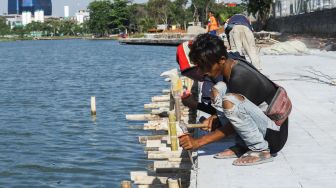 Pekerja menyelesaikan proyek revitalisasi Danau Sunter di Sunter, Jakarta Utara, Kamis (2/12/2021). [Suara.com/Alfian Winanto]