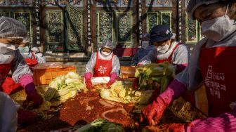 Para peserta menyiapkan kimchi, hidangan tradisional Korea dari kubis dan lobak pedas yang difermentasi, selama festival pembuatan kimchi di kuil Buddha Jogyesa, Seoul, Korea Selatan, pada (2/12/2021). [ANTHONY WALLACE / AFP]