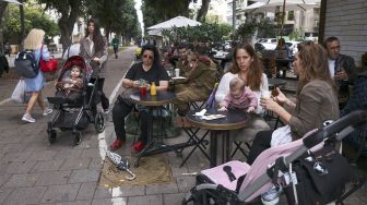 Orang-orang berada di tengah kota pesisir Mediterania Israel Tel Aviv, Israel, pada (1/12/2021). [MENAHEM KAHANA / AFP]