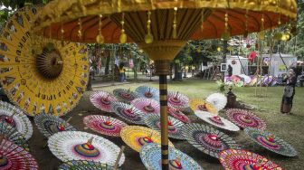 Pengunjung memotret payung yang dipamerkan pada Festival Payung 2021 di Taman Balekambang, Solo, Jawa Tengah, Jumat (3/12/2021). [ANTARA FOTO/Mohammad Ayudha]