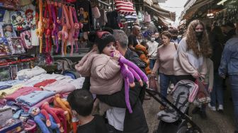 Orang-orang berada di pasar jalanan di pusat kota pesisir Mediterania Israel Tel Aviv, Israel, pada (1/12/2021). [MENAHEM KAHANA / AFP]
