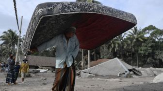 Warga mengamankan barang berharga miliknya dari rumahnya yang rusak akibat diterjang material guguran awan panas Gunung Semeru di Desa Sumber Wuluh, Lumajang, Jawa Timur, Minggu (5/12/2021). [ANTARA FOTO/Zabur Karuru]